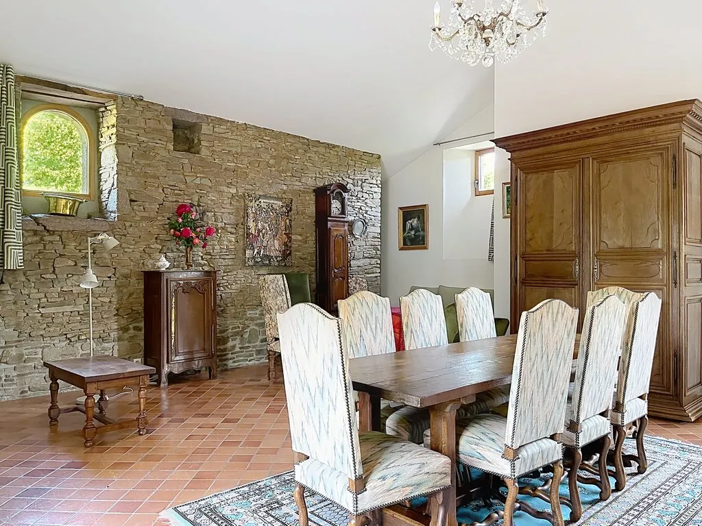 Salle à manger du gîte avec sa grande table et son mur en pierre