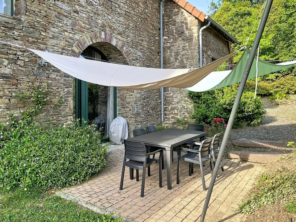Terrasse du gîte avec salon de jardin et voiles d'ombrage